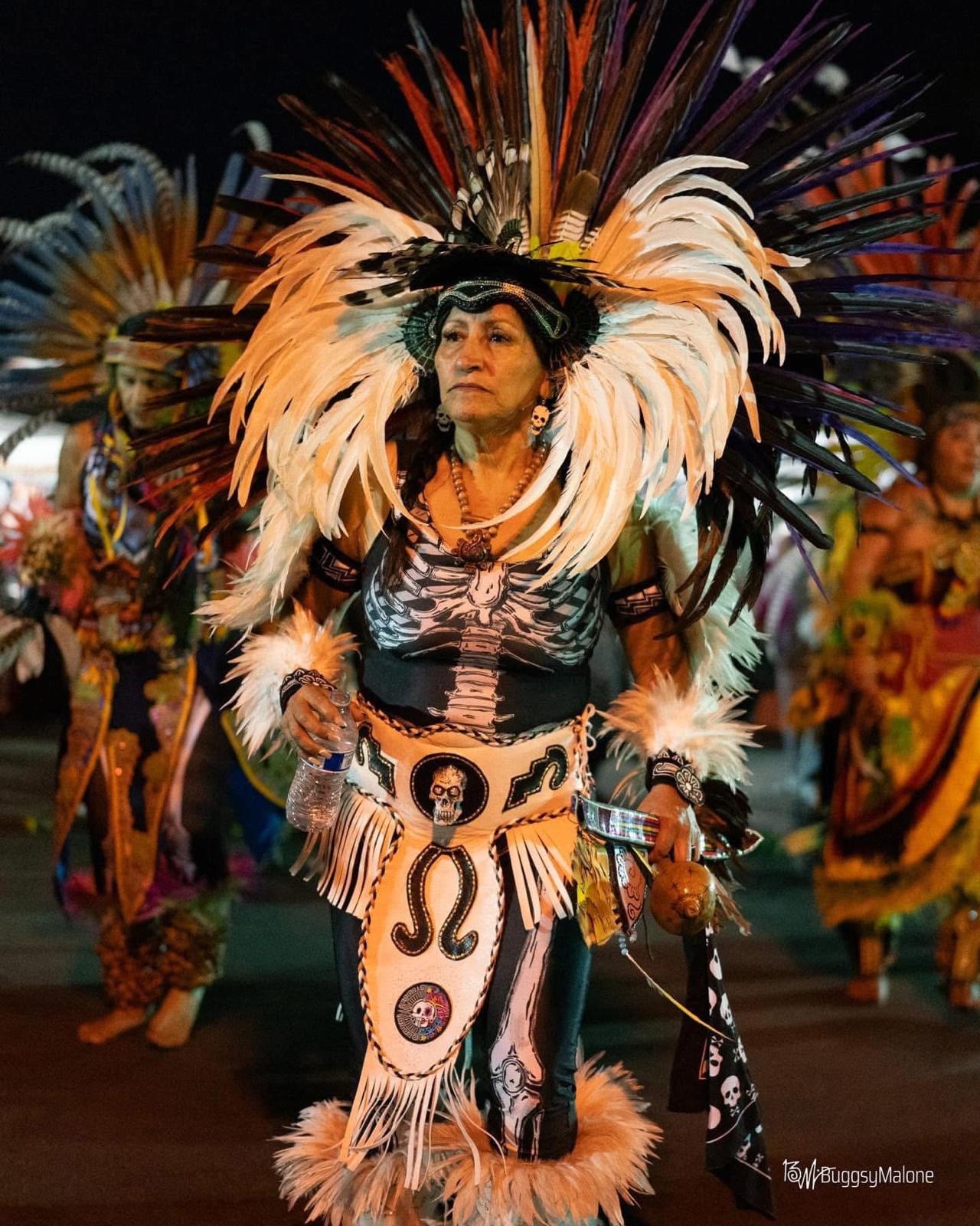 Danza Azteca performer in elaborate feathered costume at night
