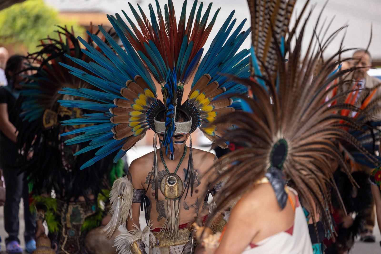 Aztec dancers with blue feathered headdresses in ceremony