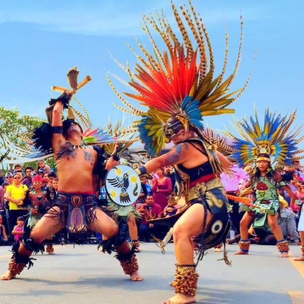 Two Aztec warriors in feathered headdresses performing combat dance